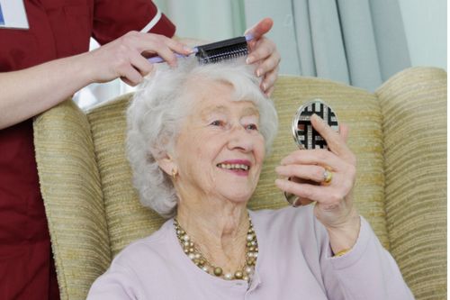 Care worker helps her elderly patients get ready by combing her hair for her